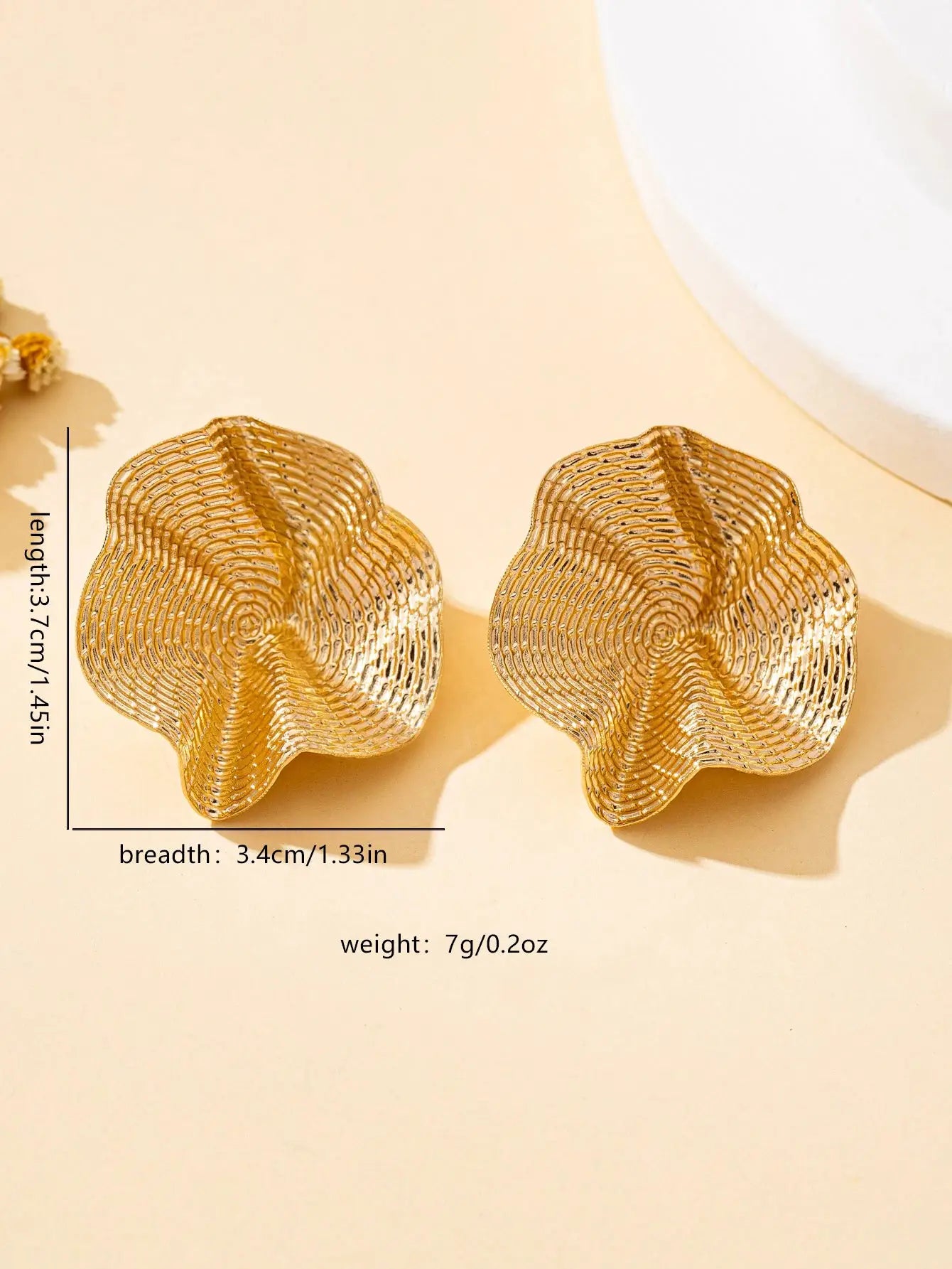 Pair of irregular round gold-tone metal stud earrings with textured swirl pattern