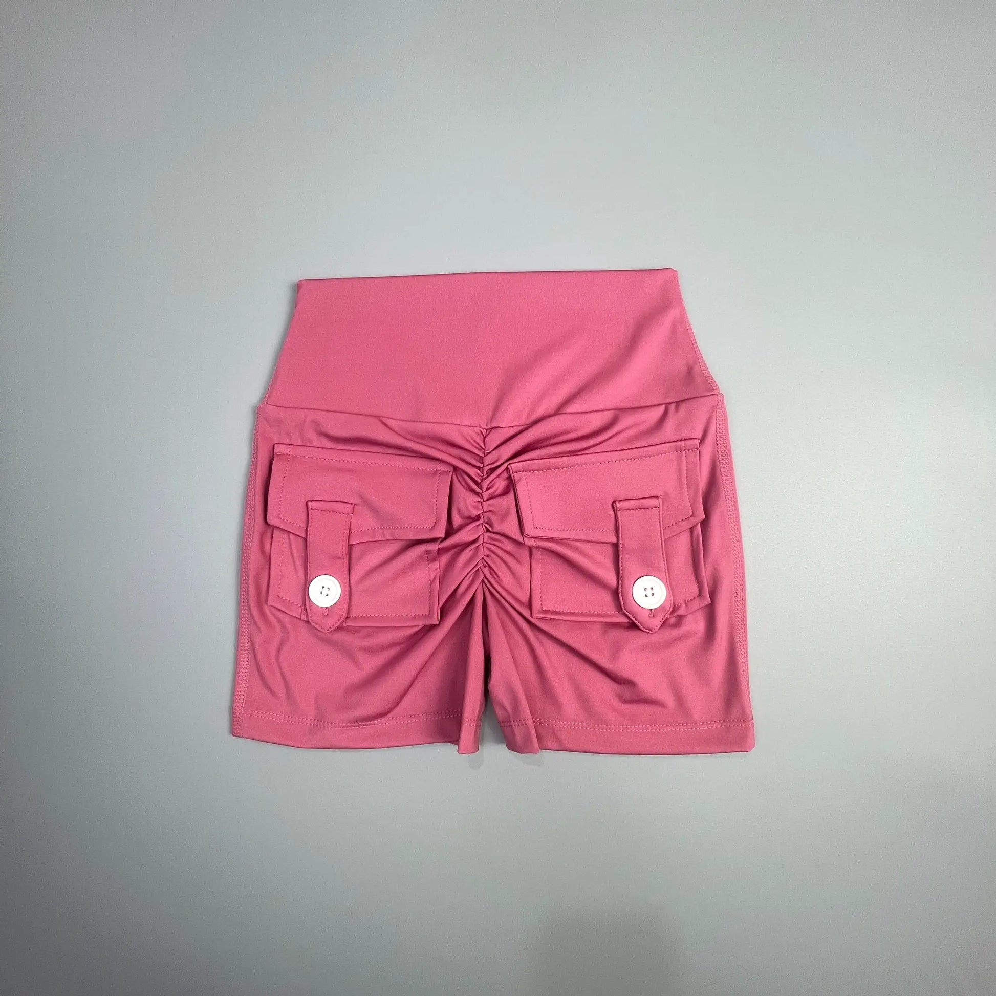 Pink women's cargo fitness shorts with front flap pockets and white buttons