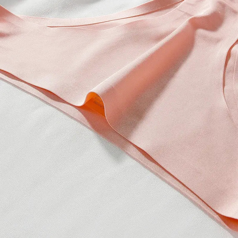 Women's pink seamless T-back thong underwear in ice-silk fabric, close-up view.