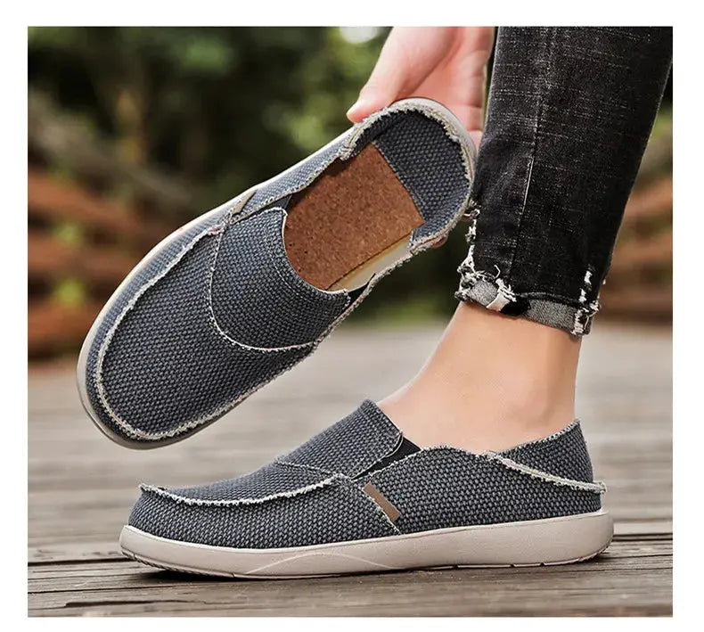 Men's gray canvas slip-on loafers, lightweight casual shoes with white soles, pair shown.