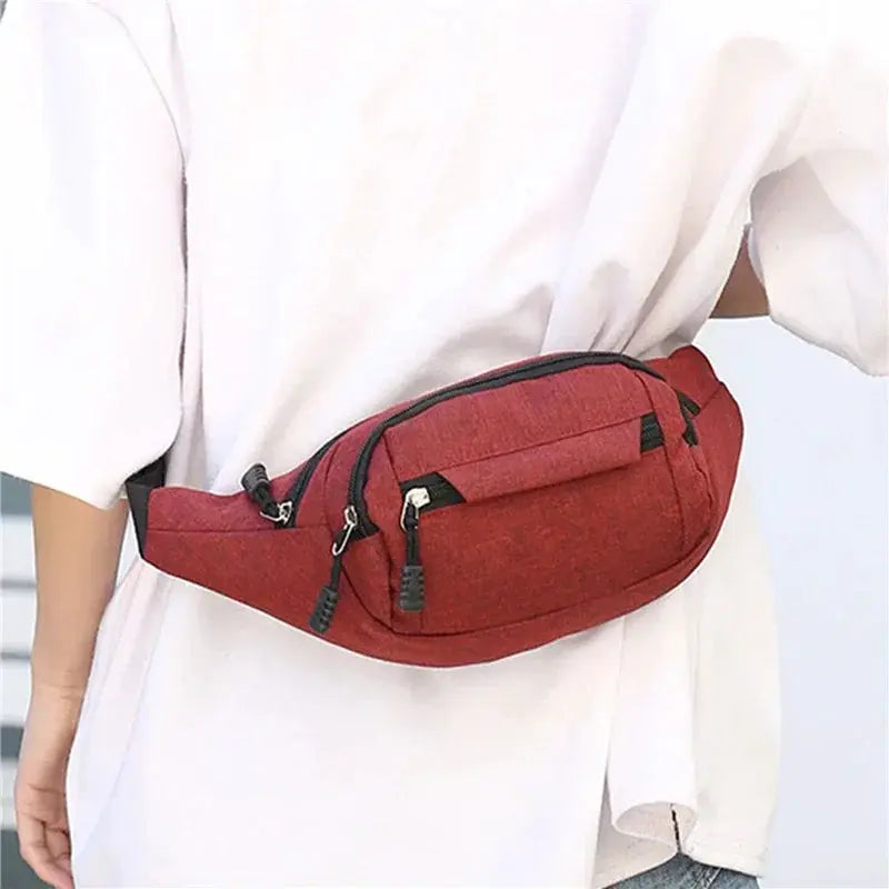 Red waist bag with multiple zip pockets worn around the waist by a person in a white top