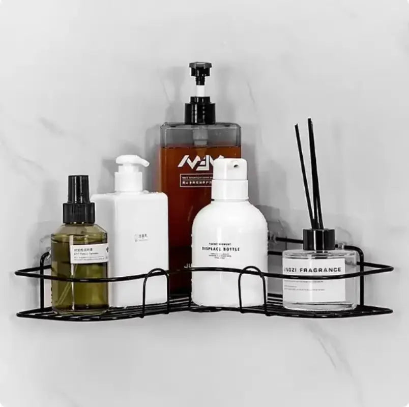 Triangle black wire wall-mounted bathroom shelf by Simples Market holding assorted bottles and a diffuser.