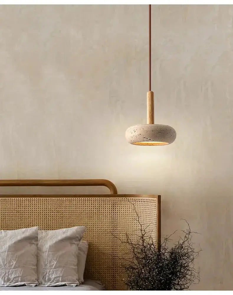 Circular yellow stone LED pendant lamp hanging from a brown cord over a bed with a rattan headboard
