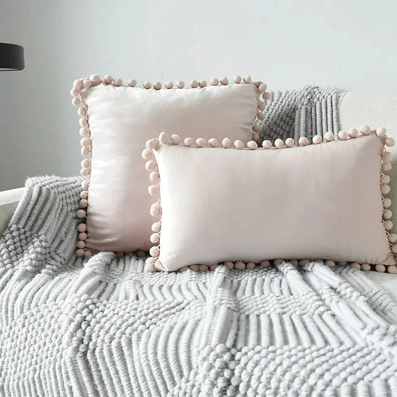 Velvet cushion covers in blush pink with tassel fringe, soft decorative sofa pillows on a gray knit throw set of 2