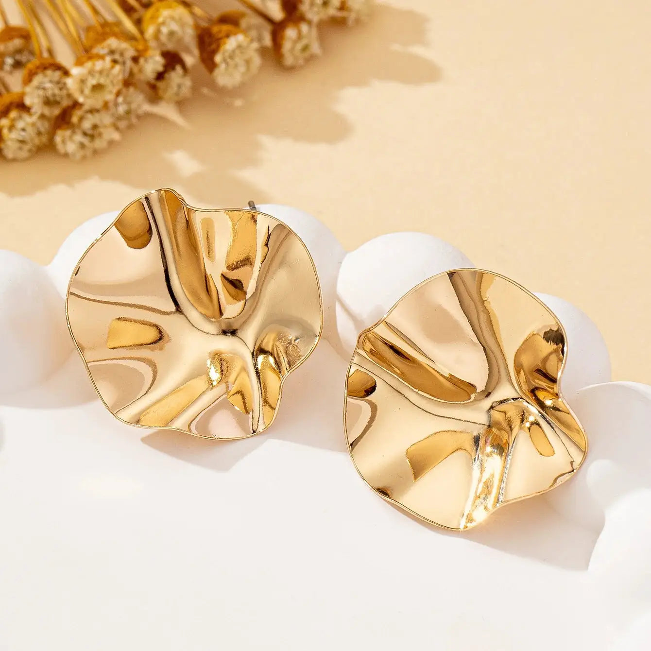 Pair of irregular round gold-tone metal stud earrings with hammered texture and reflective shine, Simples Market