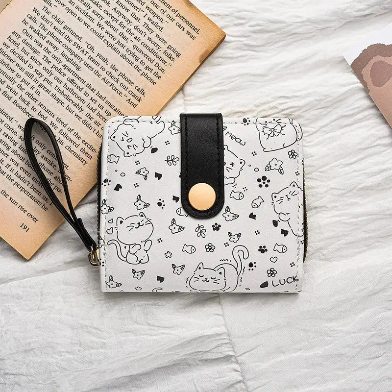Wallet with cat-print design, black strap, gold snap, zipper pocket, wrist strap