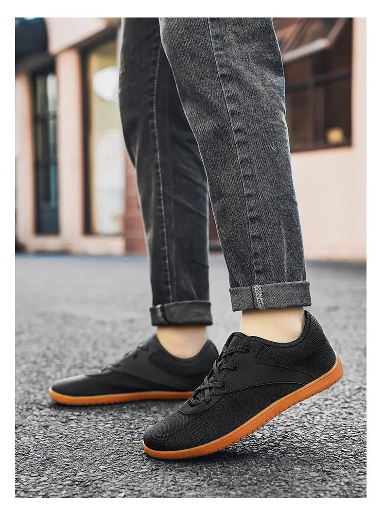 Pair of black minimalist trail running shoes with orange soles