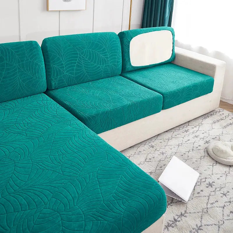 Simples Market waterproof stretch sofa slipcovers in teal with leaf-pattern, protecting three cushions on a beige sofa.