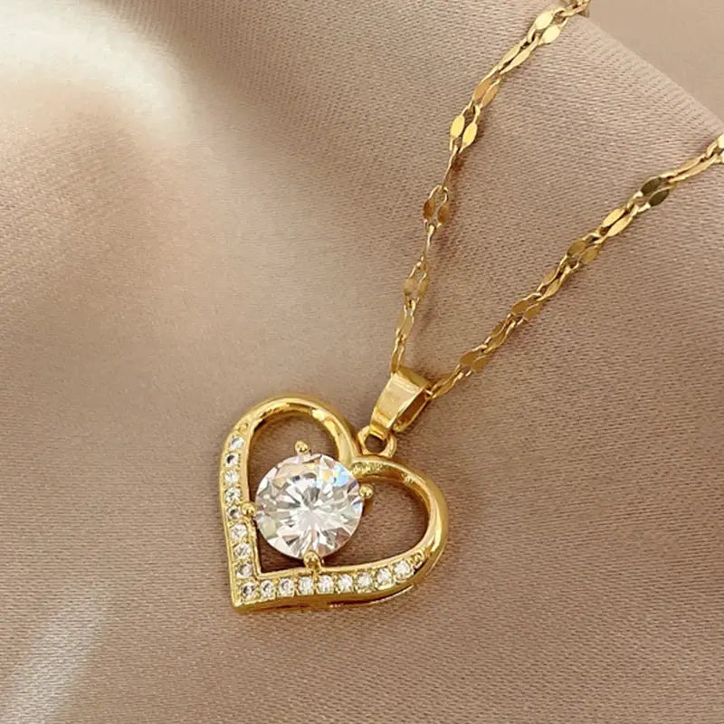 Gold heart pendant necklace with a large central crystal and pave crystals along the heart outline