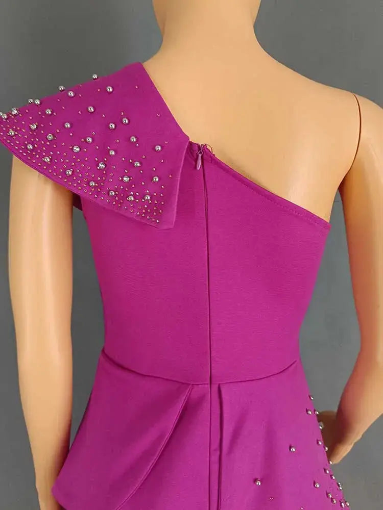 Magenta one-shoulder jumpsuit with rivet embellishments on the shoulder, back zipper, and peplum waist.