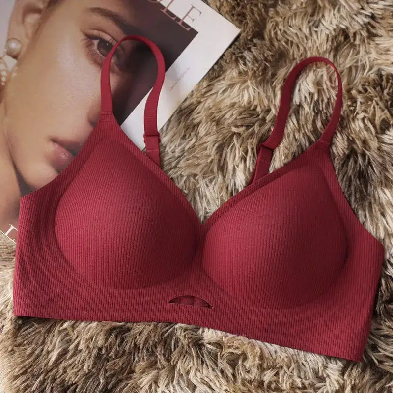 Red seamless wireless push-up bra with ribbed cups and adjustable straps on a furry rug