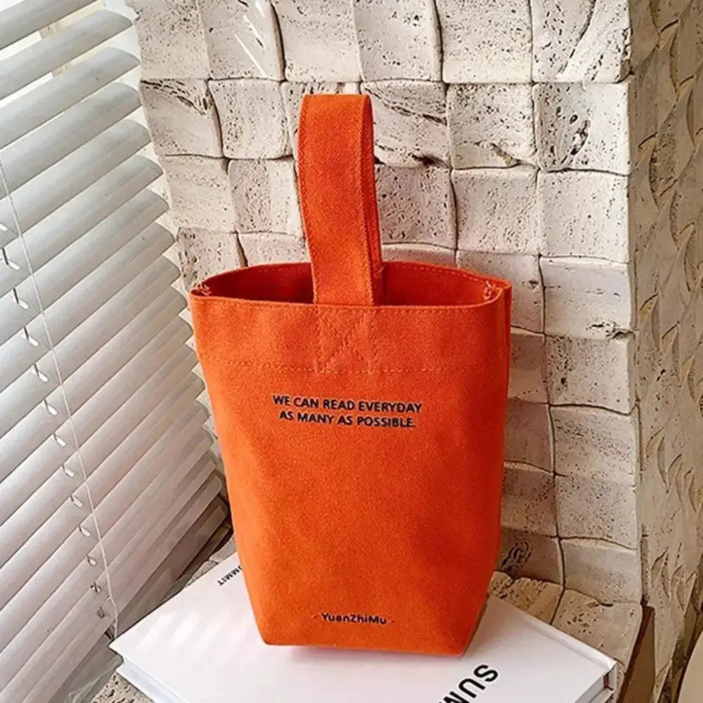 Orange canvas casual handbag with a single top handle and front slogan print, Simples Market.
