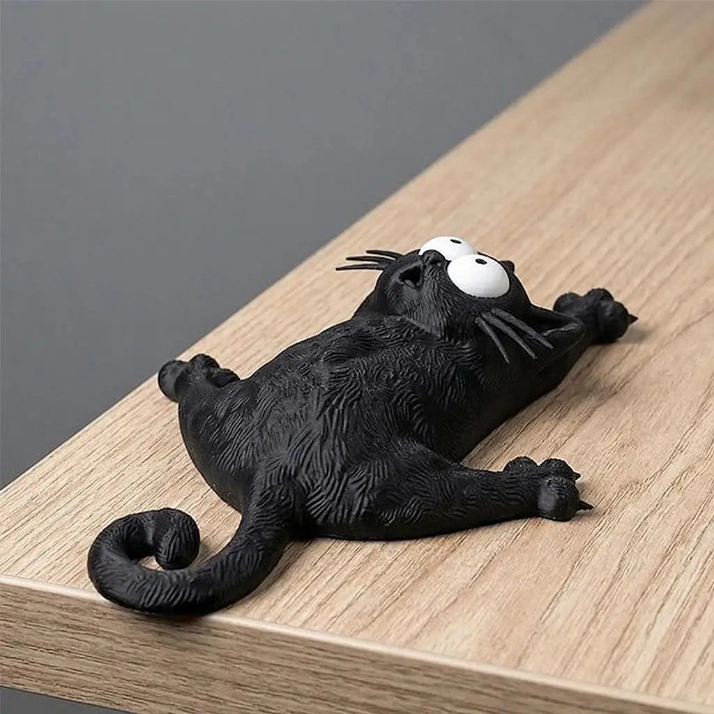 Magnetic cat refrigerator magnet, black cat with large white eyes lying on its back on a wooden surface