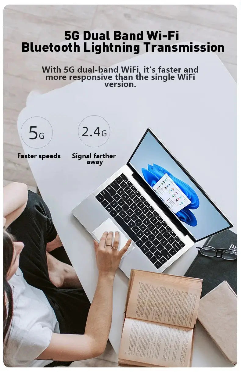 14.1-inch silver laptop open on a desk with a nearby book and glasses