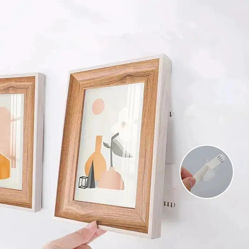 Punch-free frame tape strips for self-adhesive picture hanging; two wooden-framed prints mounted on the wall