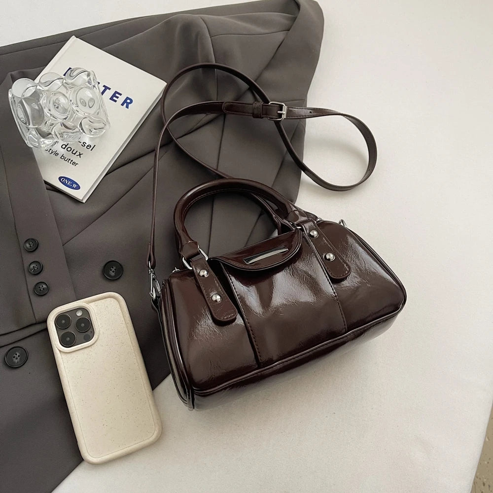 Burgundy mini top-handle bag for women in glossy PU leather with short handles and crossbody strap.