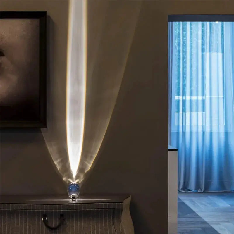 Egg-shaped LED table lamp with blue crystal base by Simples Market projecting warm light on wall