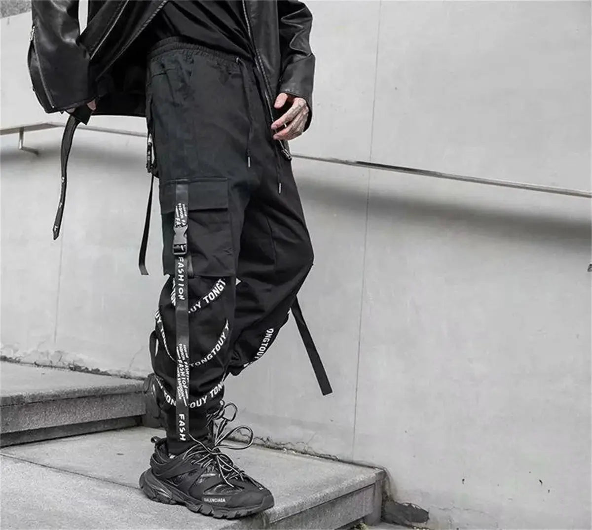 Black cargo joggers for men with ribbon strap detailing, multiple pockets and zip closures.