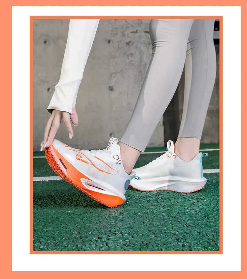 Carbon plate running shoes, white with orange outsole and turquoise heel accents, pair on green track