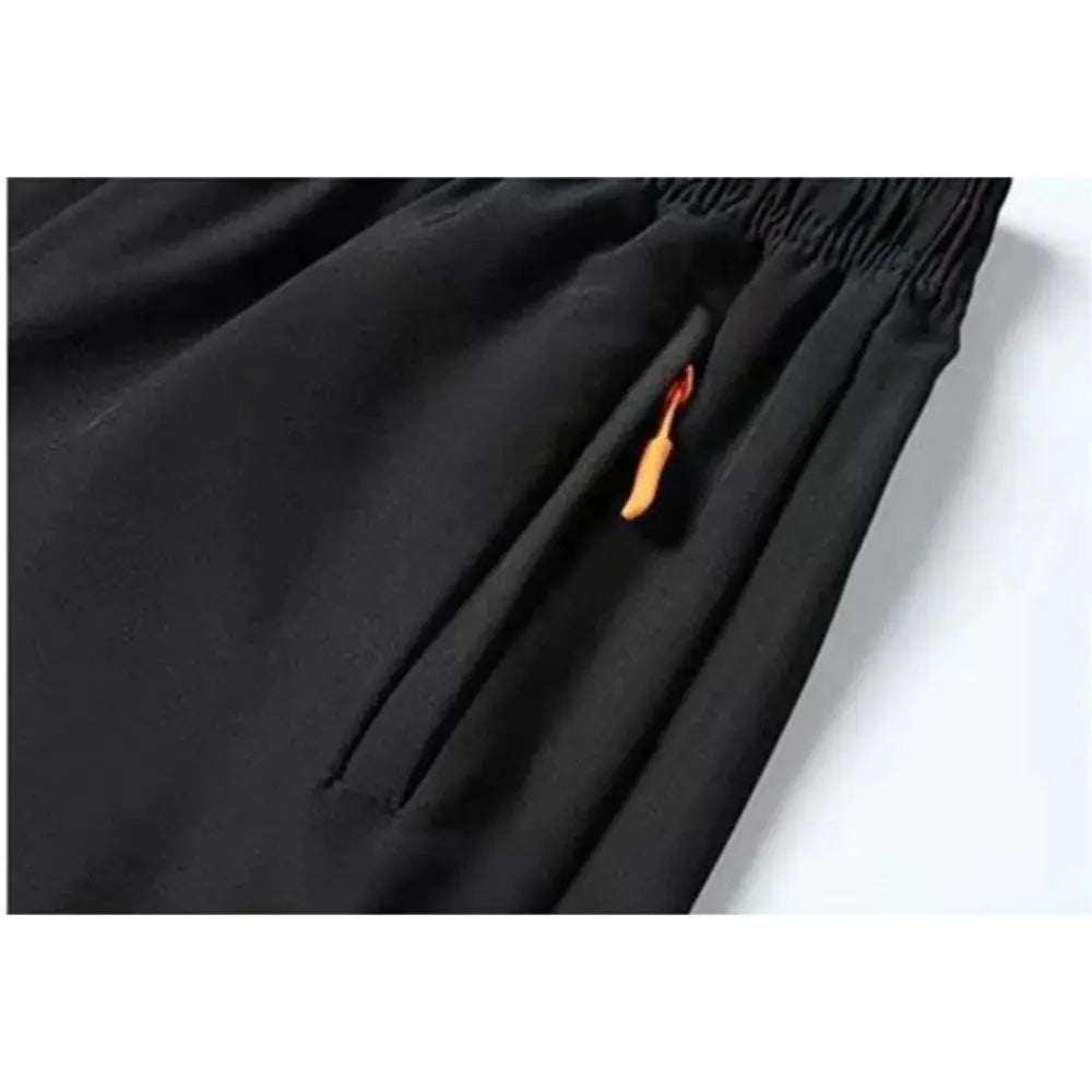 Men's black quick-dry shorts with elastic waistband and zippered side pocket, orange zipper pull