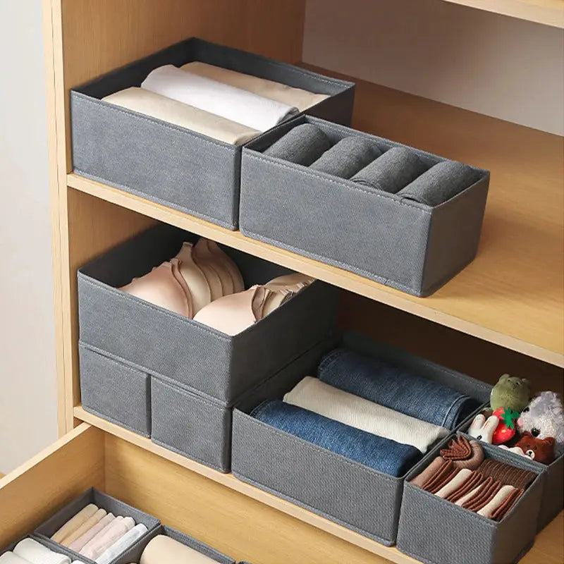 Fabric underwear storage boxes on a wooden shelf; gray fabric organizers for socks, underwear and bras.