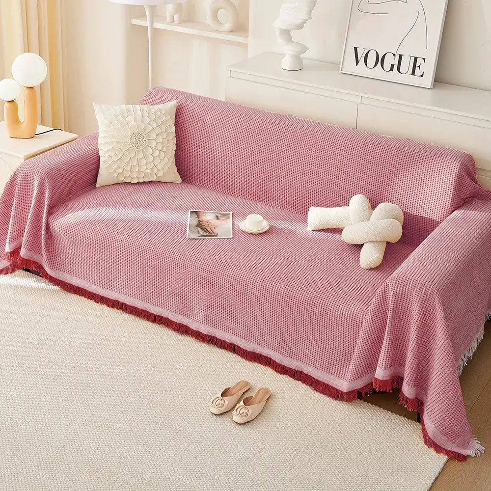Pink knit sofa throw with full-coverage design and fringed edges on a cream sofa