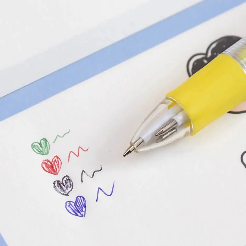 Yellow four-color kids' pen with metal tip, drawing colorful hearts on white paper.