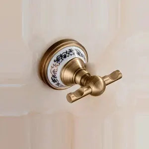 Antique brushed brass bathroom hardware with porcelain blue floral backplate and cross-handle knob