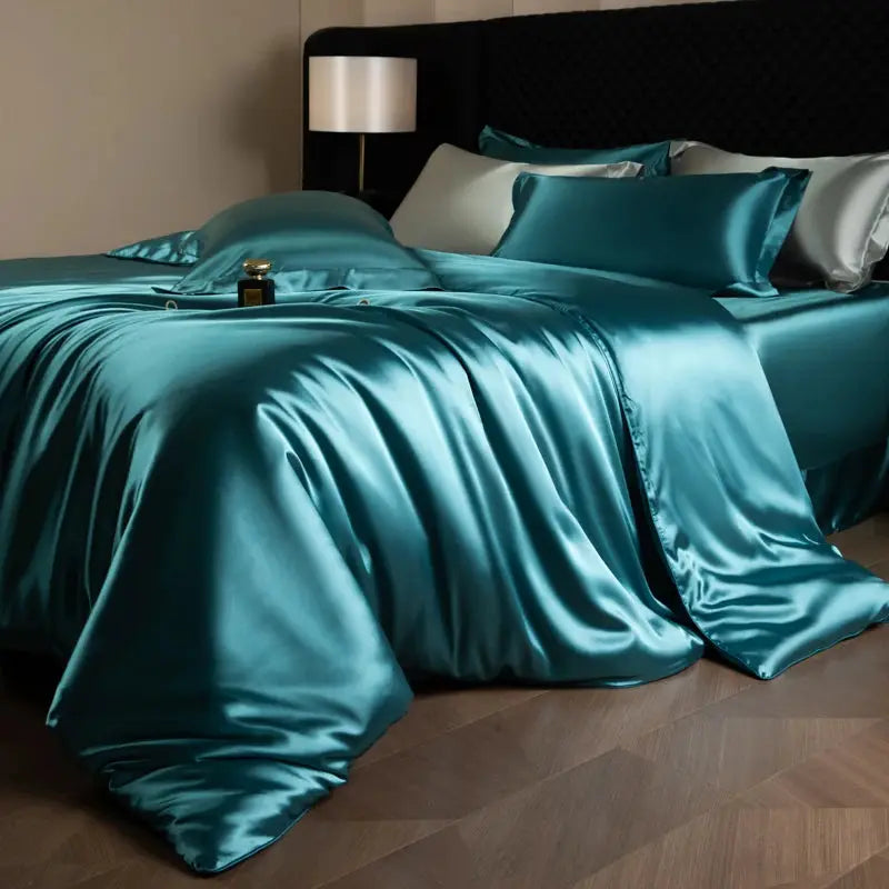Silk bed sheet set in teal satin with duvet cover, fitted and flat sheets, and pillowcases.