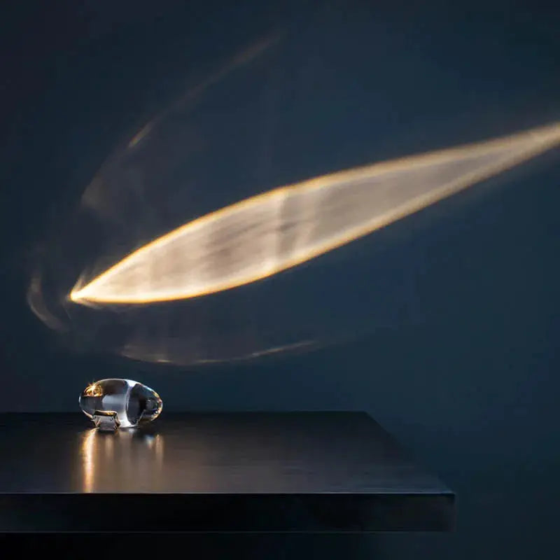Egg-shaped crystal table lamp on dark surface casting warm amber light across the wall