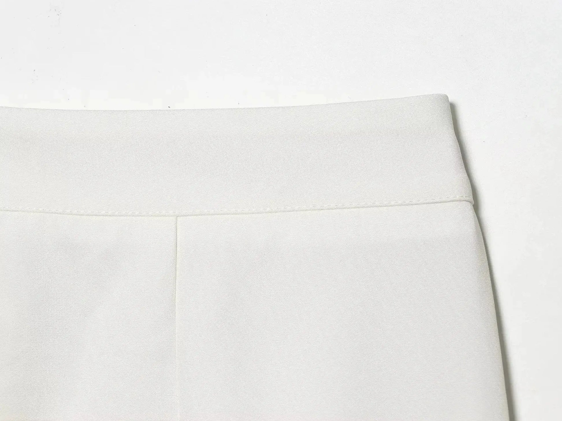 White blazer fabric close-up showing textured weave and seam detail