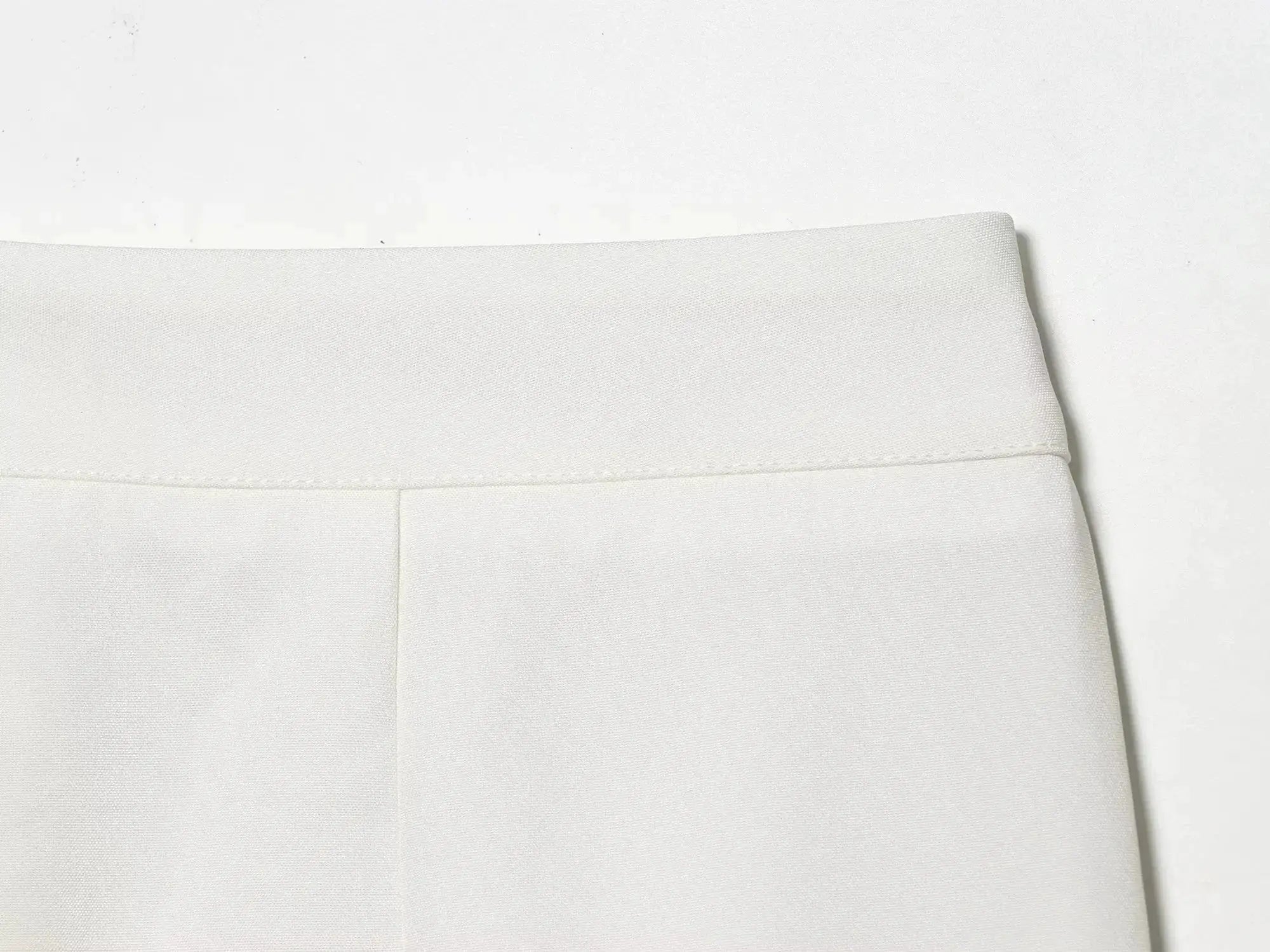 White blazer fabric close-up showing textured weave and seam detail