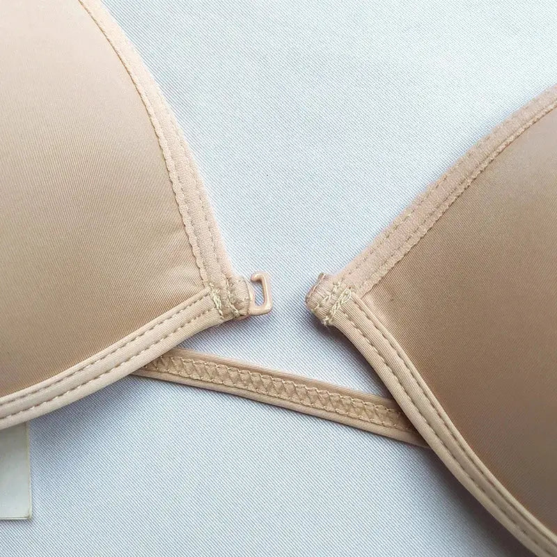 Beige seamless bra with smooth cups, thin adjustable straps and front hook clasp