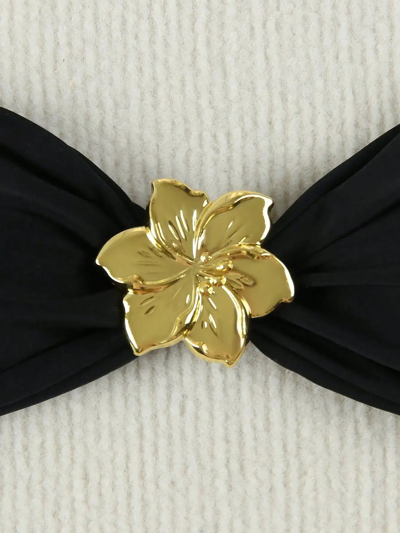Bandeau bikini top in black with a gold flower centerpiece.