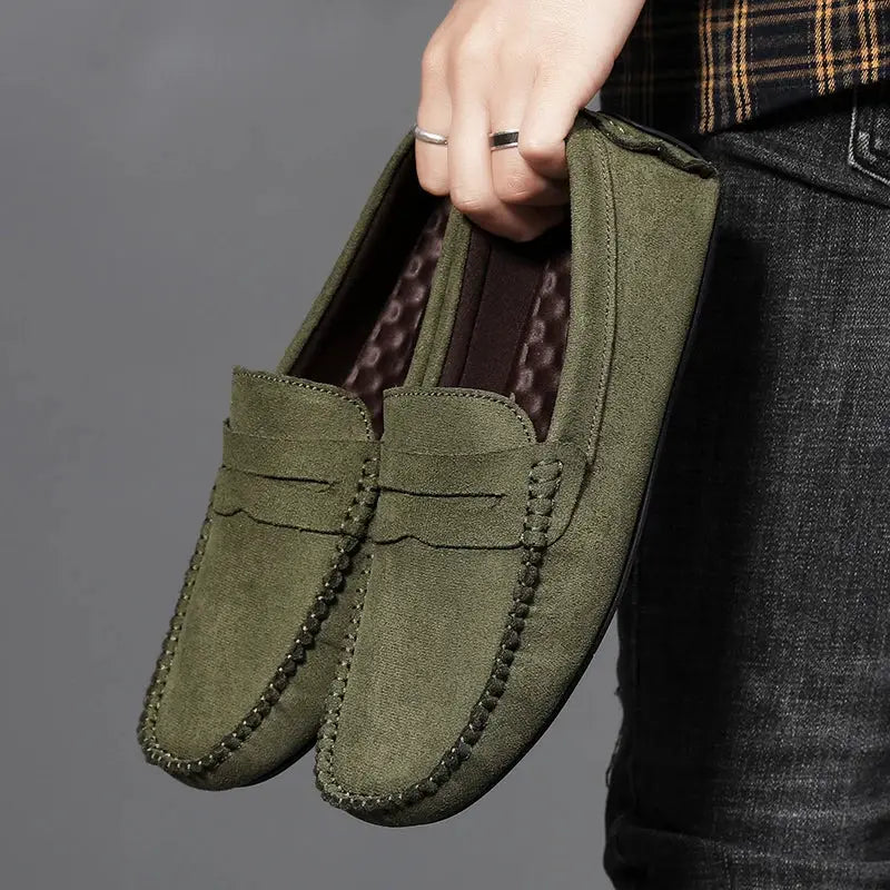 Pair of olive green suede loafers, slip-on driving shoes with visible moccasin stitching