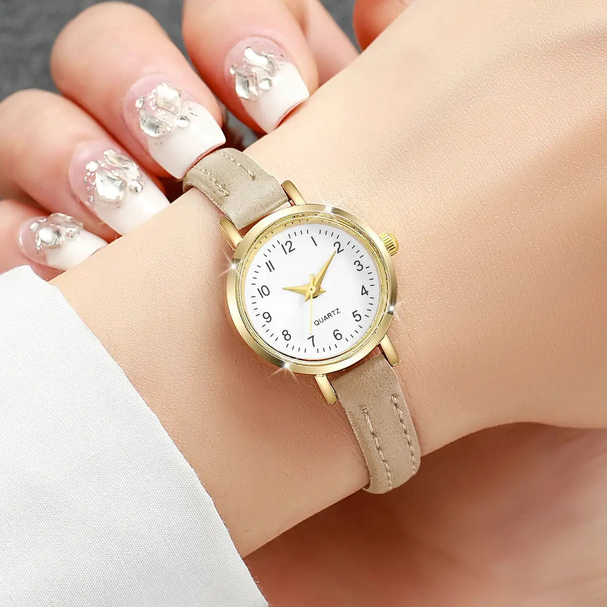 Women’s gold-tone quartz watch with beige leather strap and white dial.