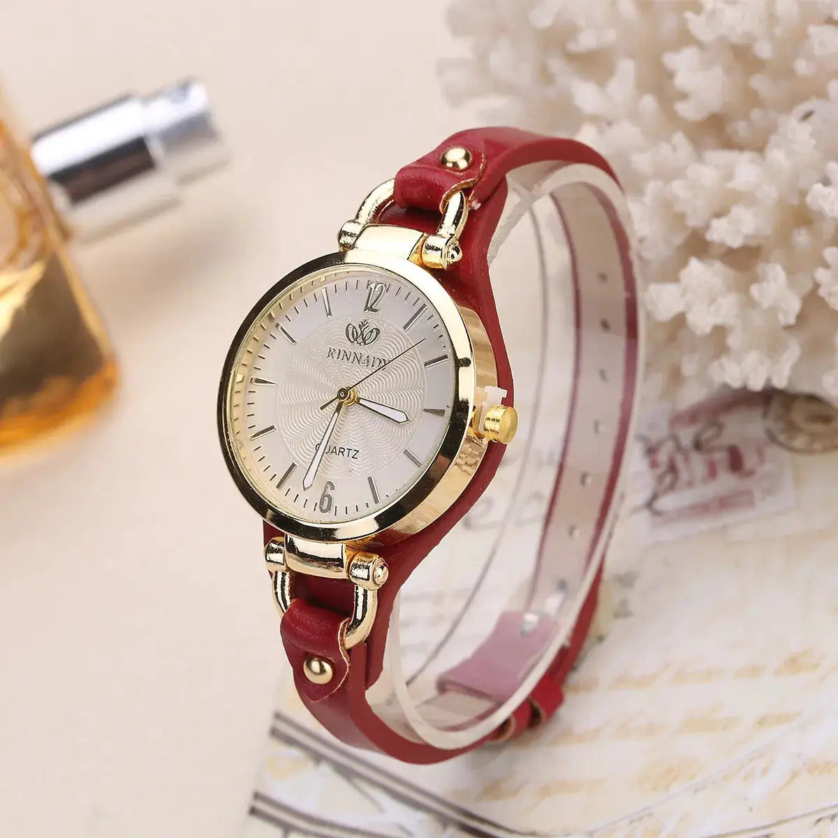 Women's fashion minimalist quartz watch with red leather strap and gold-tone case.