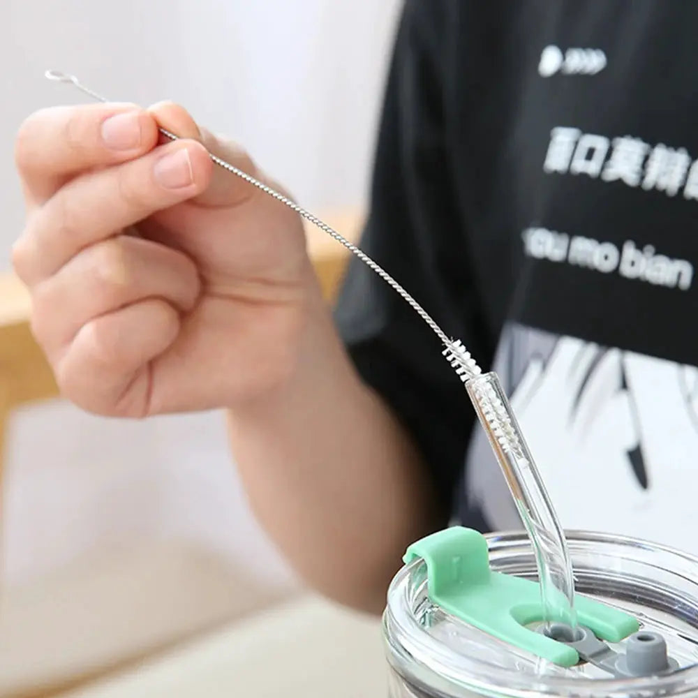 Drinking straw cleaning brush kit with a long stainless steel wire brush and nylon bristles, shown cleaning a reusable cup straw.