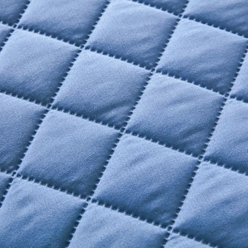 Blue quilted cotton pillowcase with a square patch pattern.