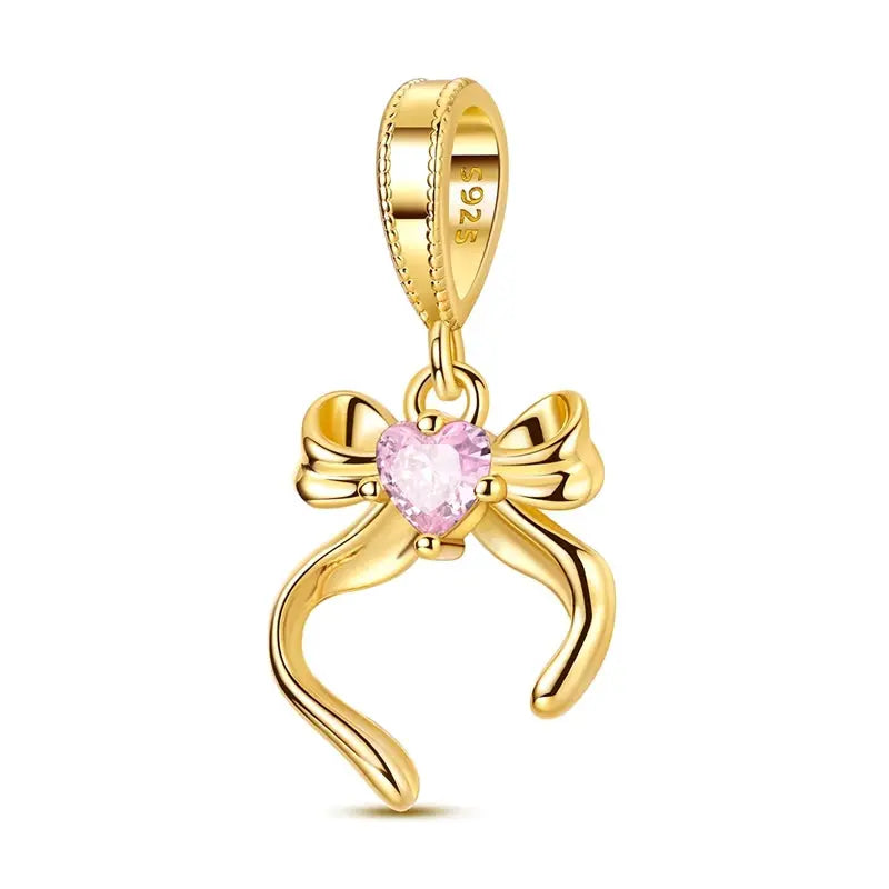 Gold-tone bow charm pendant featuring a pink heart gem and 925 bail for original bracelets