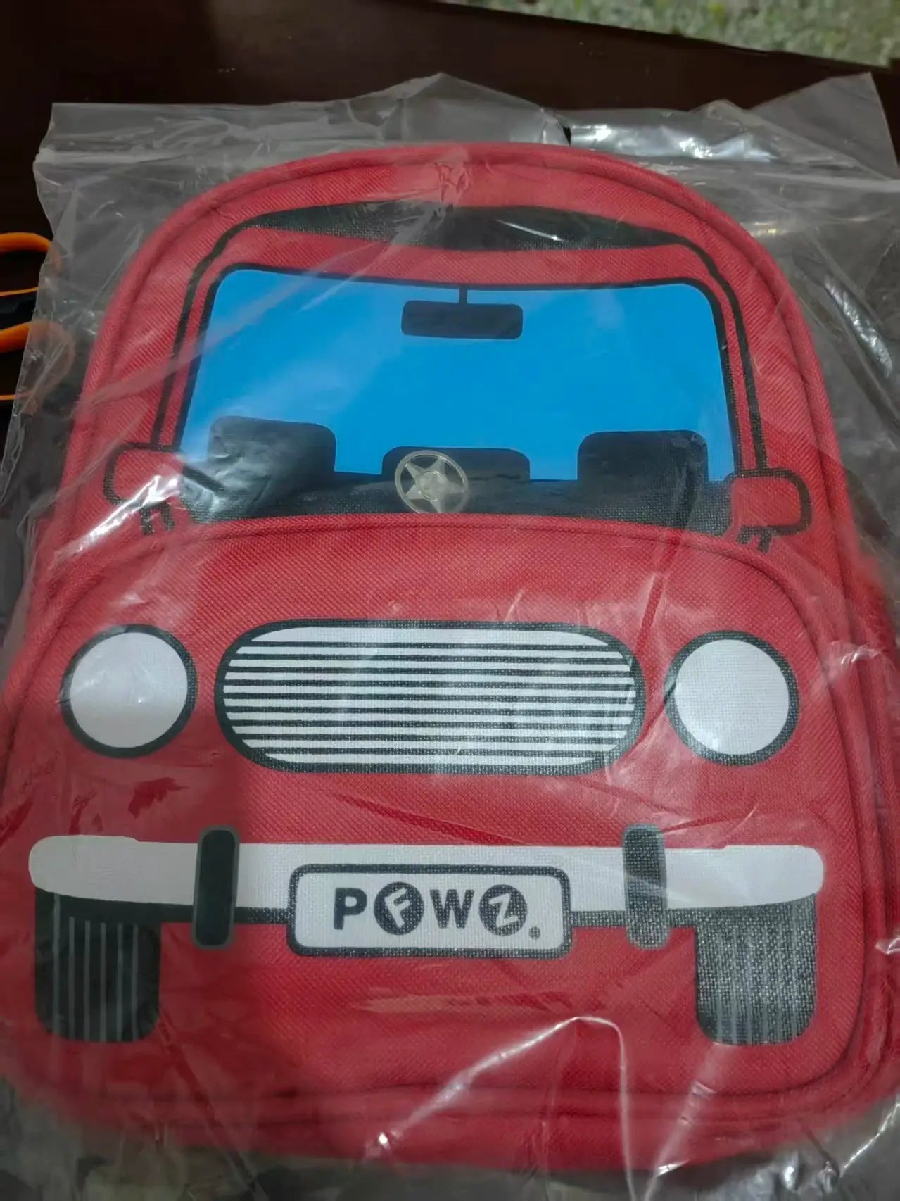 Red children's police car backpack with blue windshield panel and front grill design.