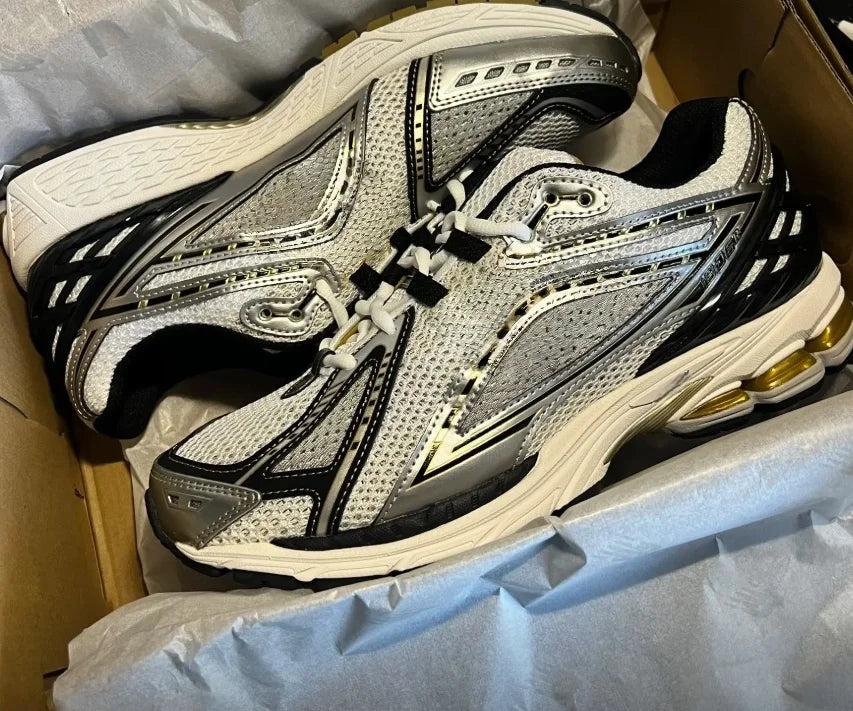White and gray mesh running sneakers with black overlays and gold heel pods in a box.