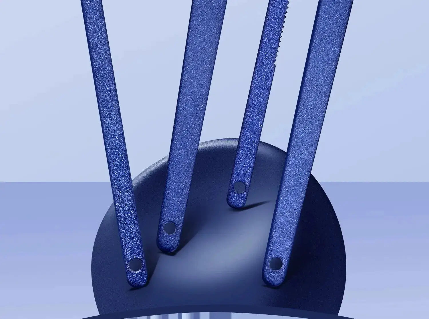 Nail tool set with four blue glitter stainless steel handles arranged around a dark circular stand