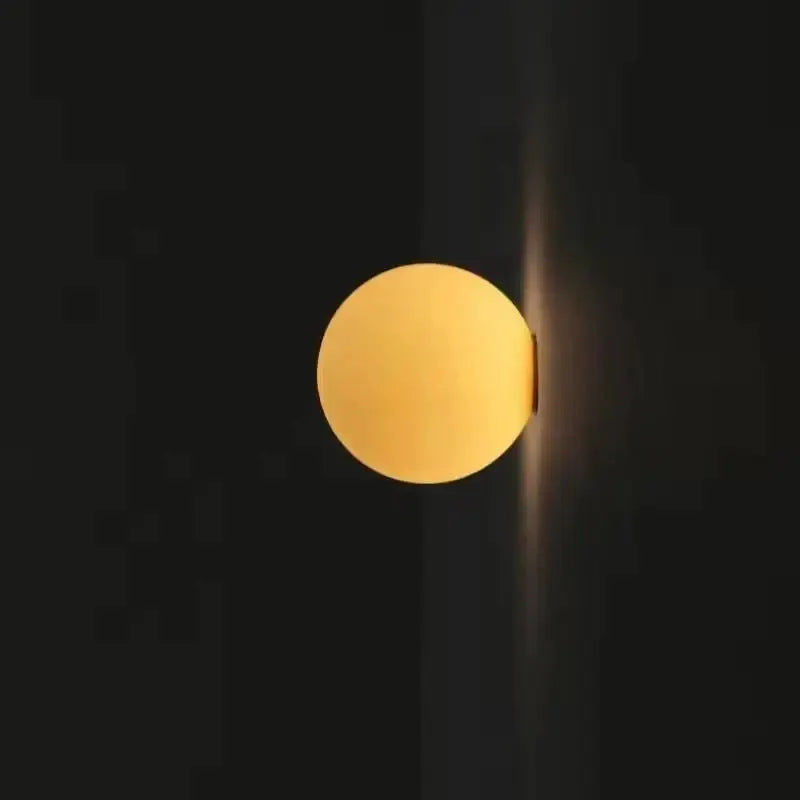Milky white glass ball wall lamp by Simples Market; frosted round wall light with warm glow.