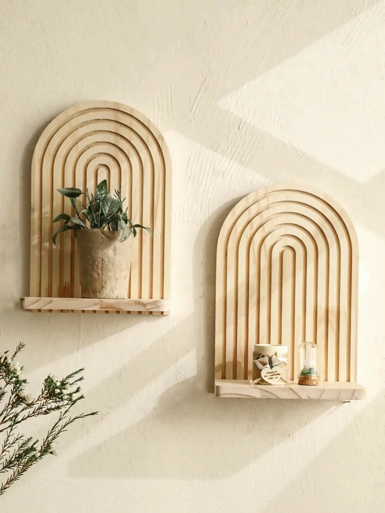 Two boho style geometric wooden wall shelves with nested arches in natural finish, plant display on left.