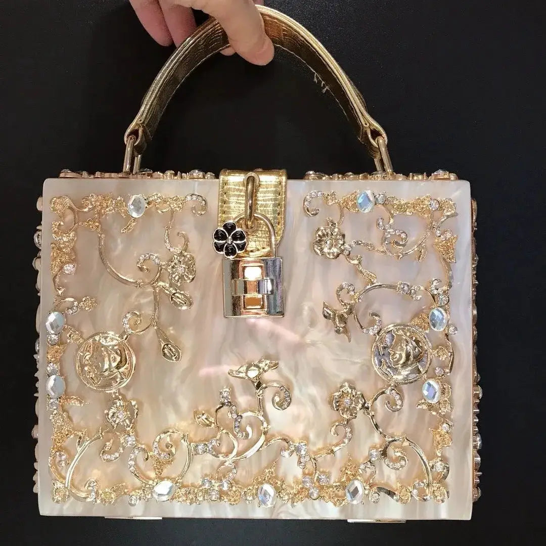 Box-style evening bag with pearlescent shell surface, gold-tone crystal floral filigree, and lock clasp.