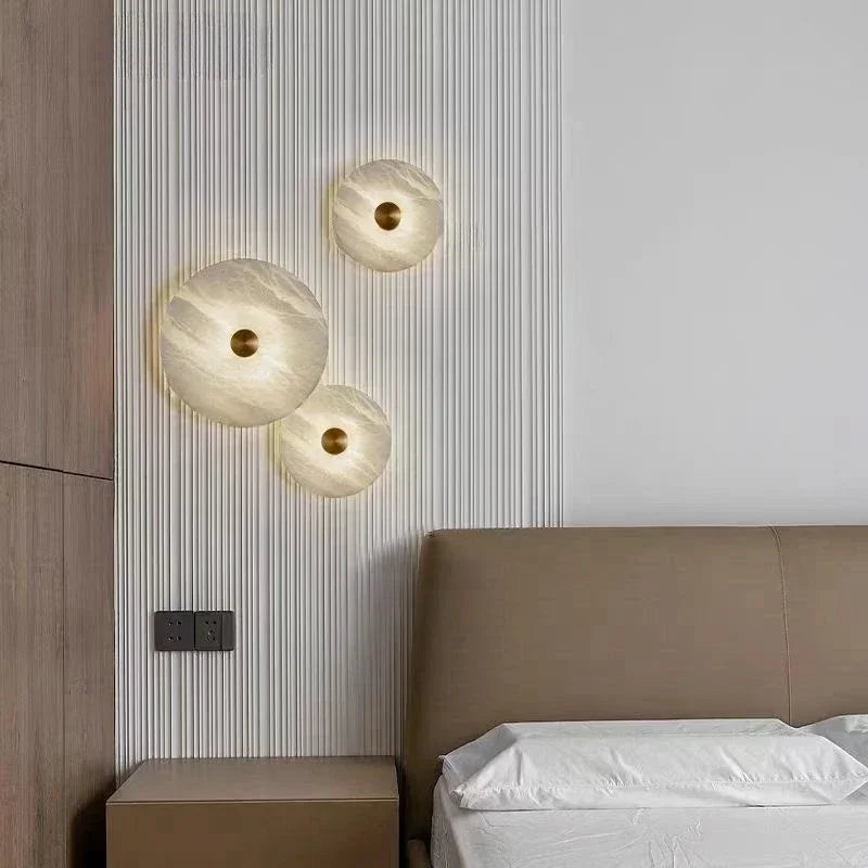 Luxury natural marble wall lamp trio with copper LED spheres on a ribbed panel beside a bed