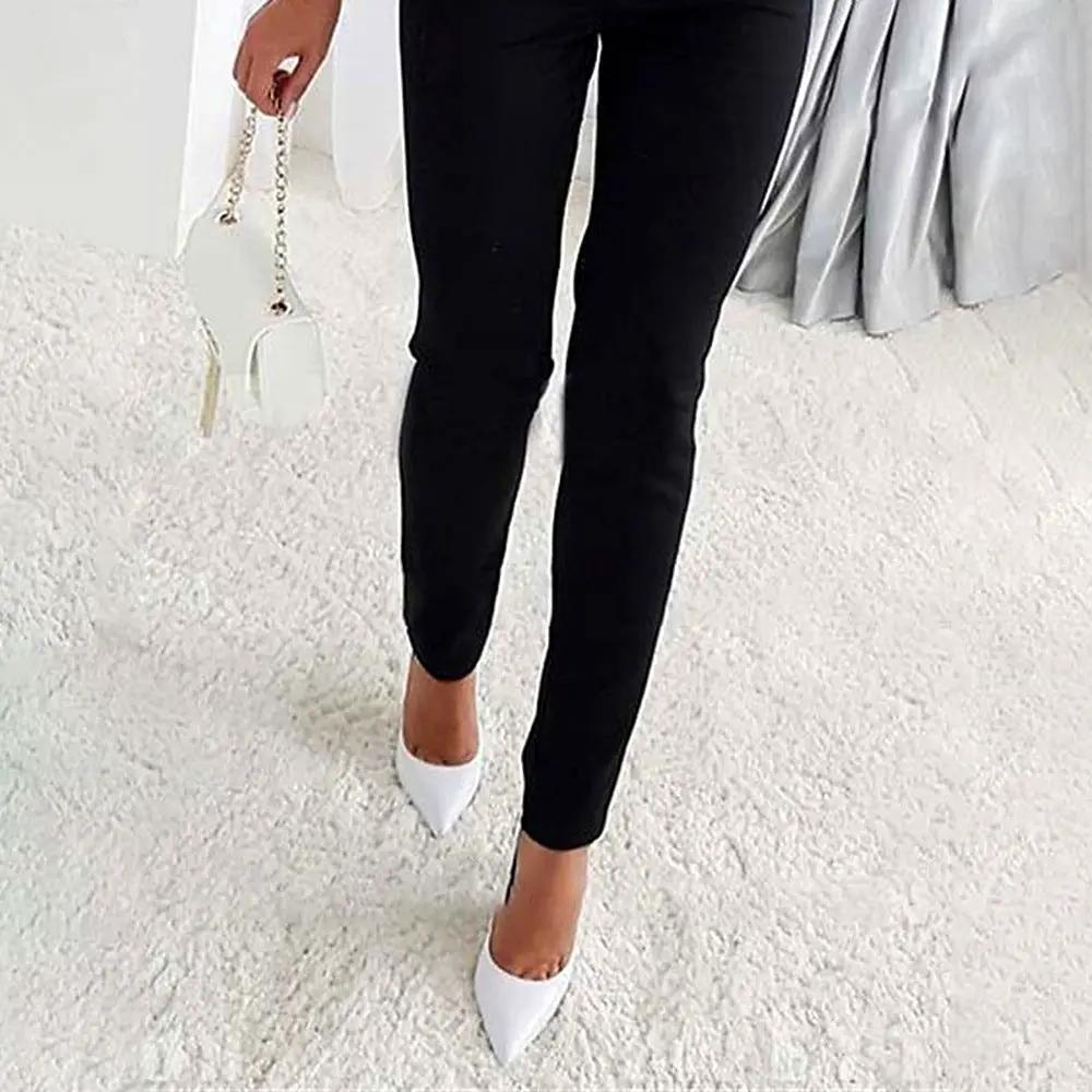Women's black jumpsuit, slim-fit one-piece, paired with white pointed-toe heels and a white handbag.