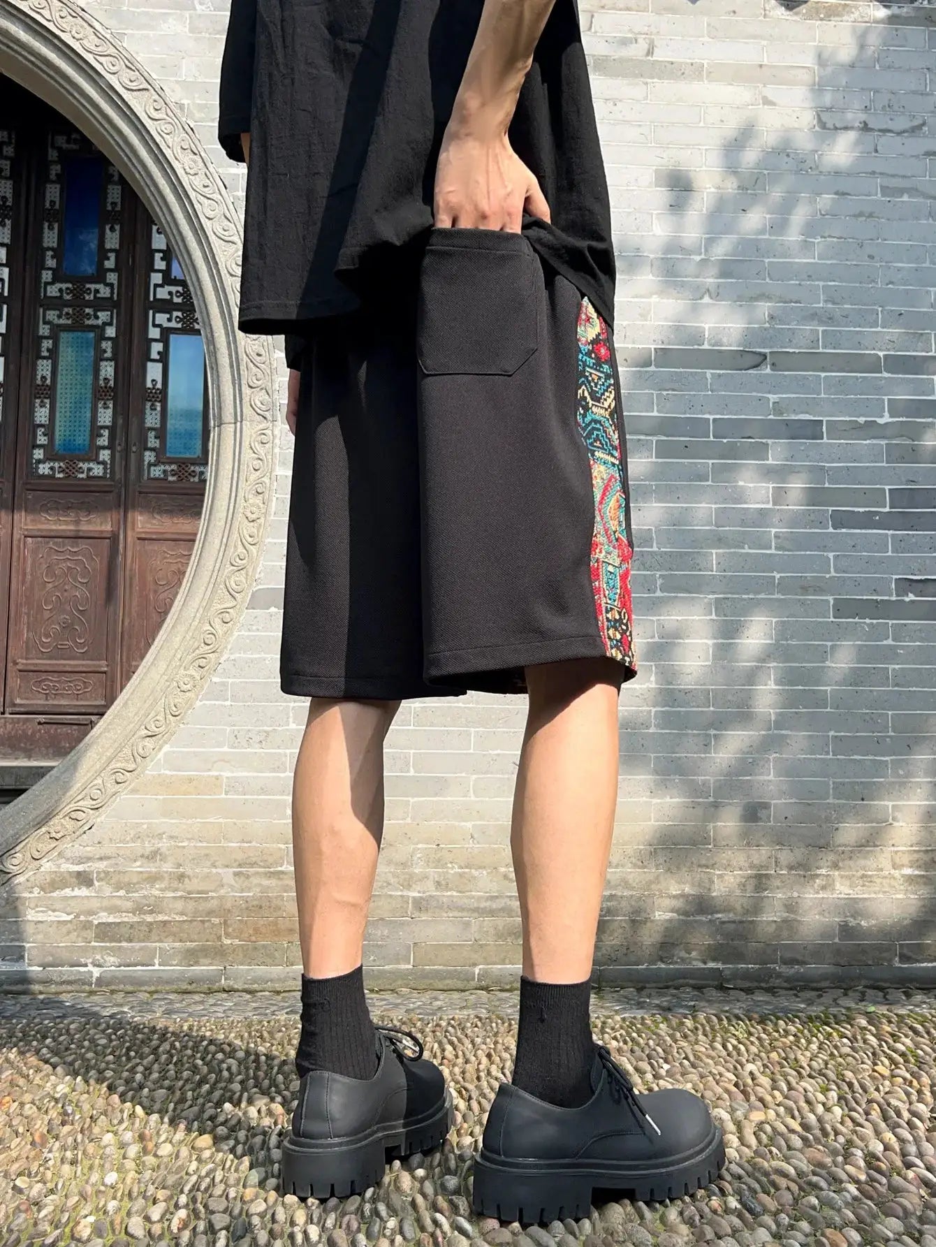 Men's black shorts with colorful ethnic embroidery side panel and pockets.