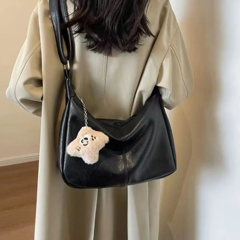 Trendy slouchy shoulder bag for women in black PU leather with teddy bear charm, large-capacity hobo tote.